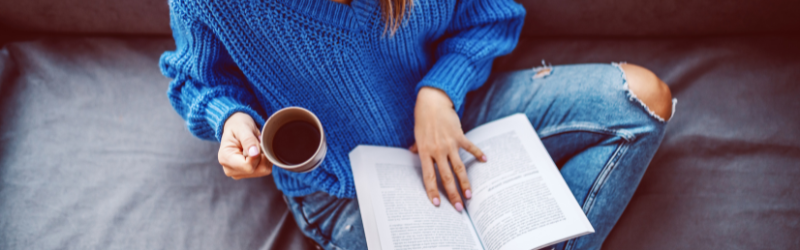 γυναίκα κρατάει κούπα καφέ και βιβλίο